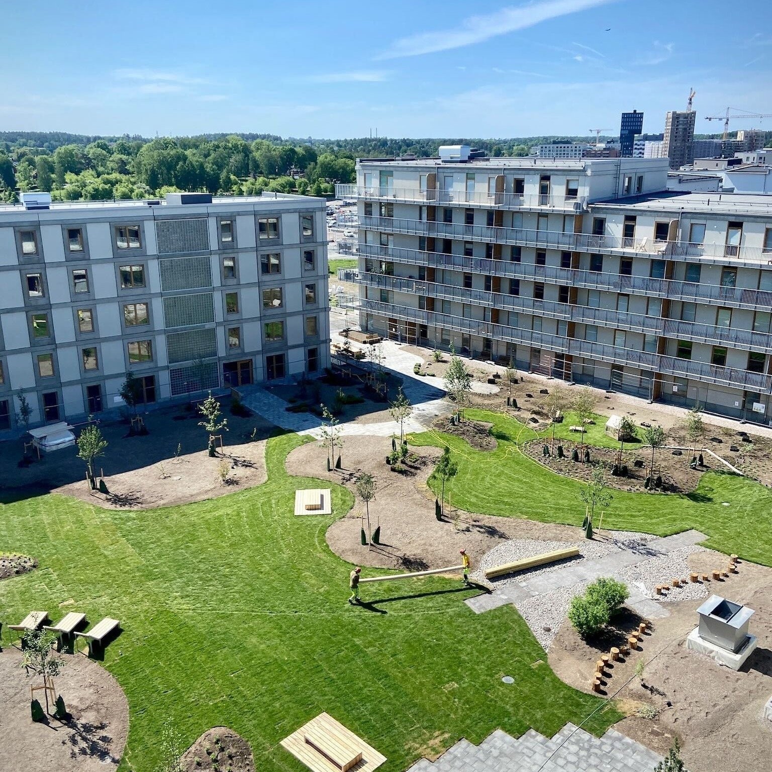 Neubau-Wohnanlage mit mehreren Mehrfamilienhäusern und begrünter Gartenfläche.